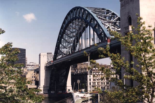  A colour photographic print showing the Tyne Bridge from Gateshead Quayside. The tall black building on the left-hand side of the picture is Cale Cross House.